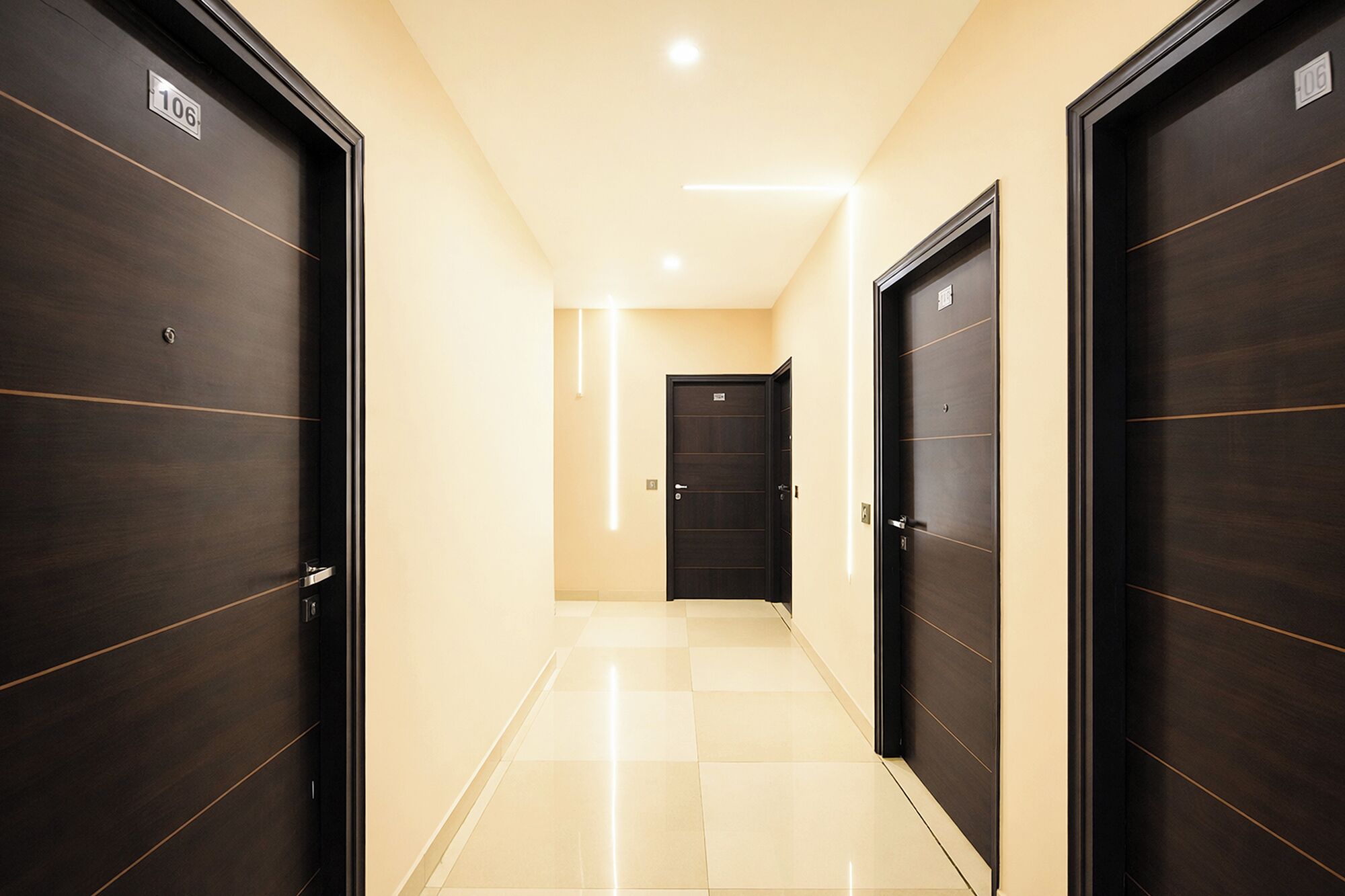 A hallway with dark wooden doors, light-colored walls, and a checkered floor.