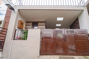 A gated entrance with a metal gate, a small wooden box on the wall, and a staircase leading to an upper level. - FabHotel All Season's Stays (Ootacamund)
