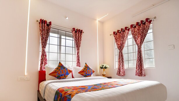 A neatly arranged bedroom with a bed, pillows, and curtains. - FabHotel All Season's Stays (Ootacamund)