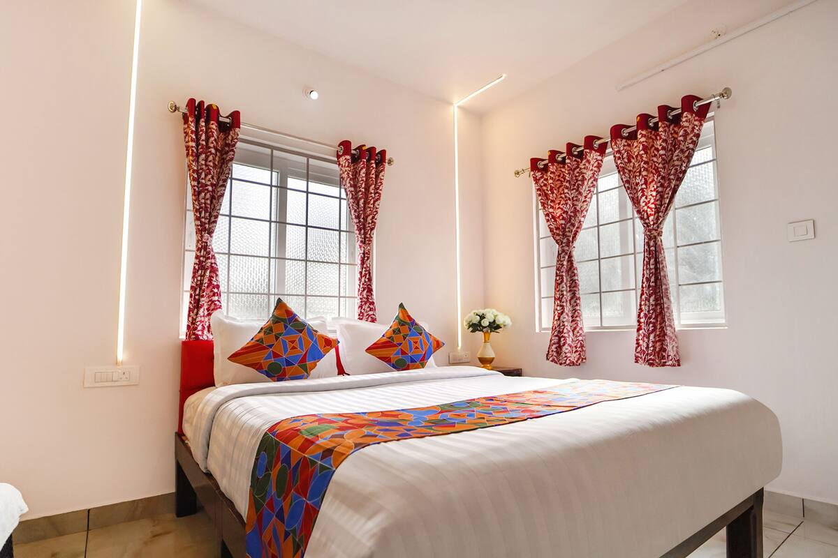 A neatly arranged bedroom with a bed, pillows, and curtains.