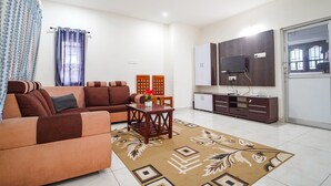 A living room with a sofa, a coffee table, and a TV. There is a cabinet and a window with curtains. - FabHotel All Season's Stays (Ootacamund)