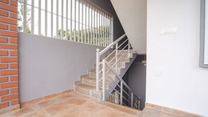 A staircase with white railings and patterned steps, leading to a landing with a window and a power outlet. - FabHotel All Season's Stays (Ootacamund)