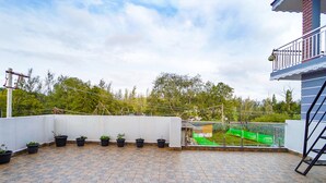 A rooftop terrace with potted plants arranged in a row, a clear view of the surrounding greenery, and a balcony with a railing. - FabHotel All Season's Stays (Ootacamund)