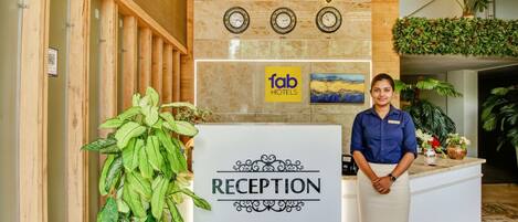 A reception desk at Hotel Manjeet with a 'fab hotels' sign, a clock, and a reception sign.