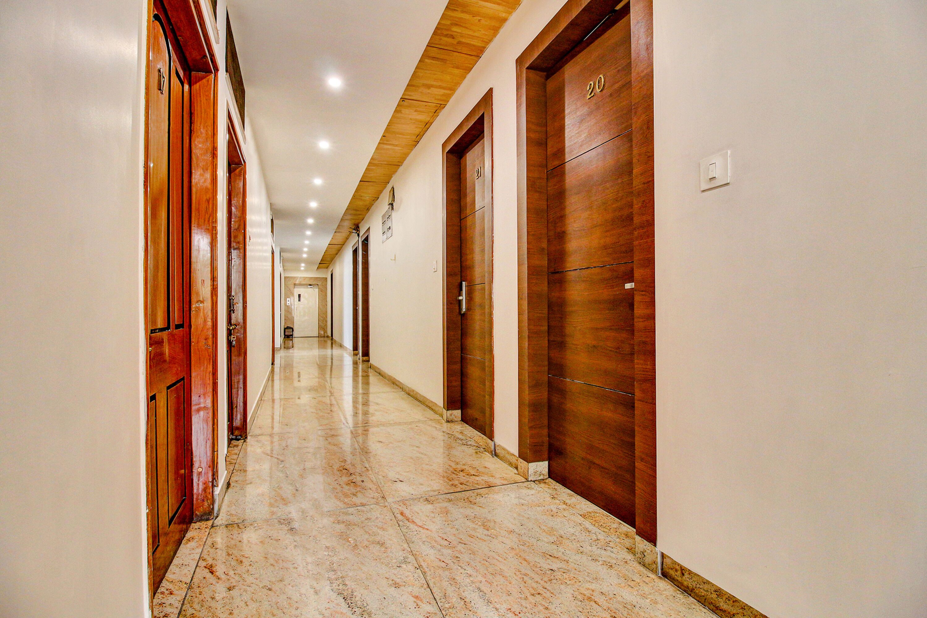 Un pasillo largo y estrecho con puertas de madera a ambos lados, numeradas 20 y 21, y un piso de mármol.
