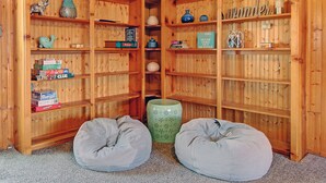 Une pièce d’angle avec des étagères en bois où sont rangés des livres, des objets décoratifs et une pancarte indiquant « SALON ».