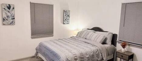 A bedroom with a bed, a nightstand, and two wall-mounted light fixtures.