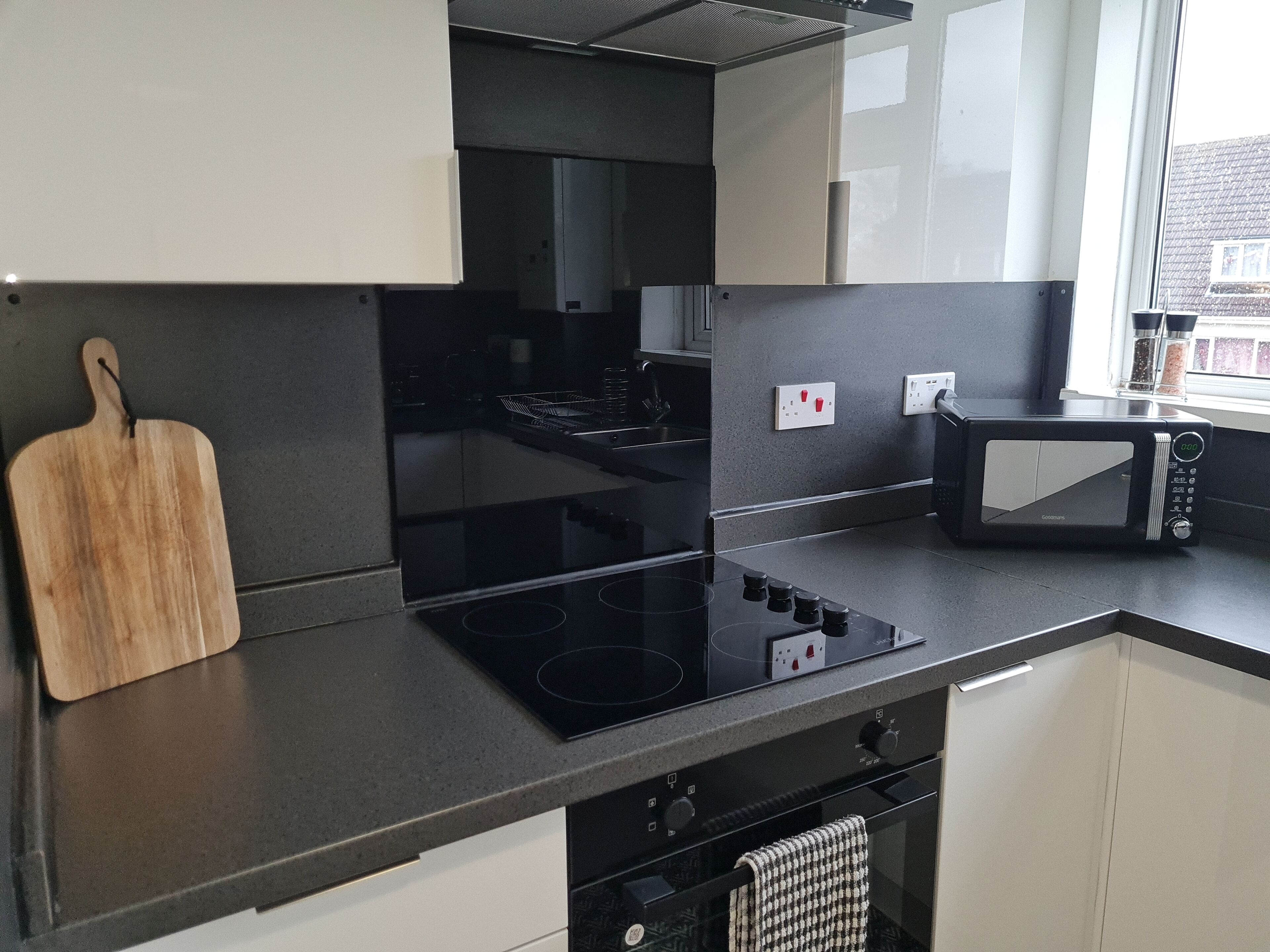 A modern kitchen with a black induction cooktop, a microwave, and white cabinets.