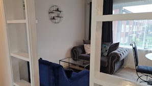 Ein Wohnzimmer mit einer Couch, einem Couchtisch und einem an der Wand befestigten Regal mit Pflanzen.
