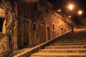 Uma escadaria de pedra que leva a um edifício com portas em arco e uma parede de pedra.