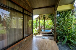 Un intérieur en bois, avec de grandes fenêtres, un plancher en bois et une vue sur un jardin extérieur avec une piscine.