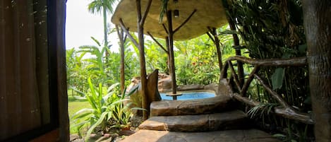 A tropical outdoor area with a hot tub, stone steps, and lush greenery.