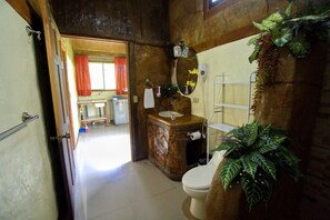 Une salle de bain au décor rustique, comprenant un meuble-lavabo en bois, des toilettes blanches et un miroir avec un cadre décoratif.
