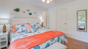 Ein Schlafzimmer mit Bett, Nachttischen, Deckenventilator und einer Tür.