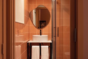 Un baño con un espejo redondo, un lavabo y un perchero para toallas.