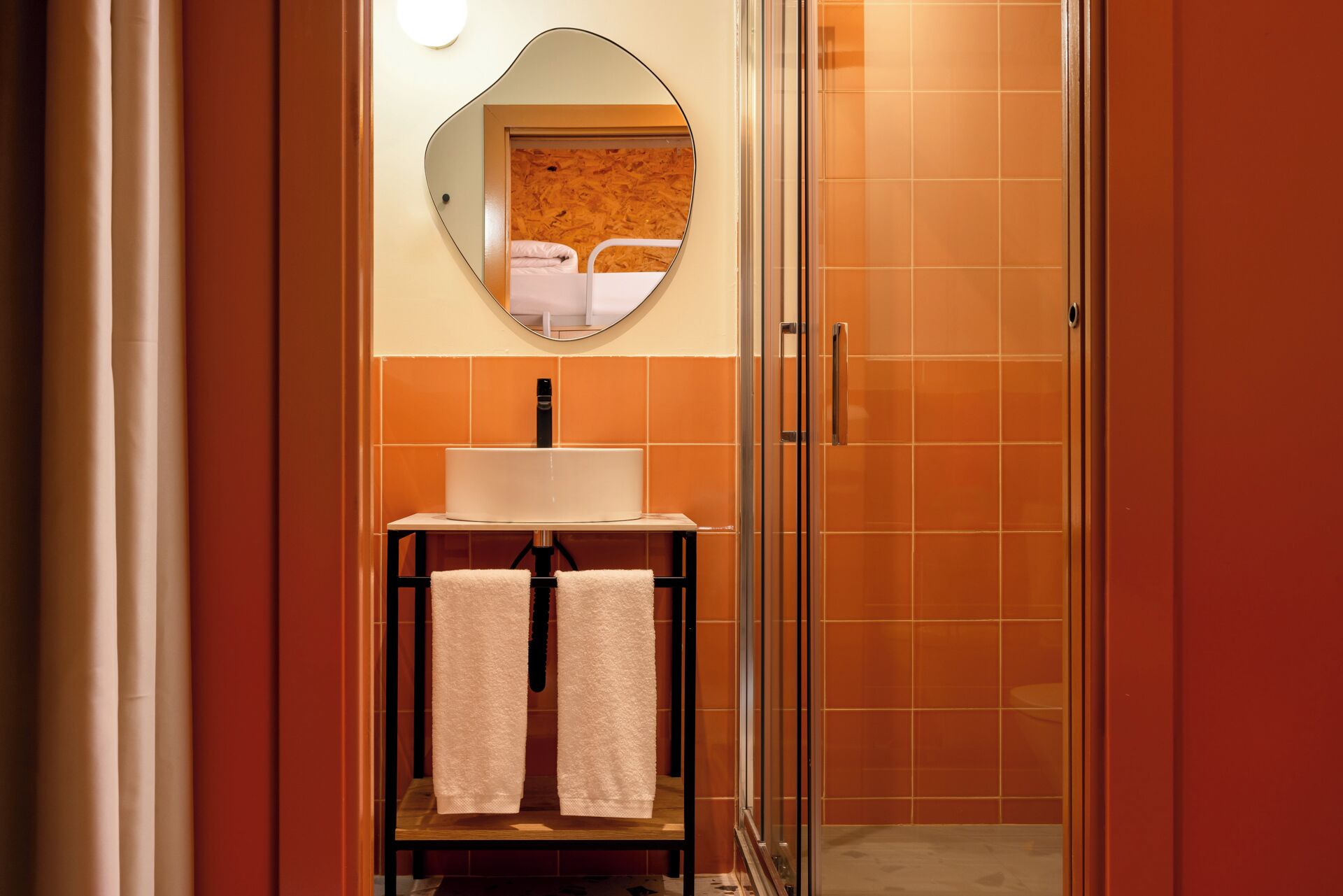 A bathroom with a white sink, a mirror, and a towel rack with two towels.