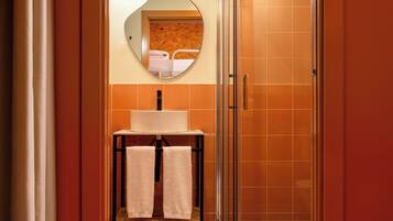 A bathroom with a white sink, a mirror, and a towel rack with two towels.