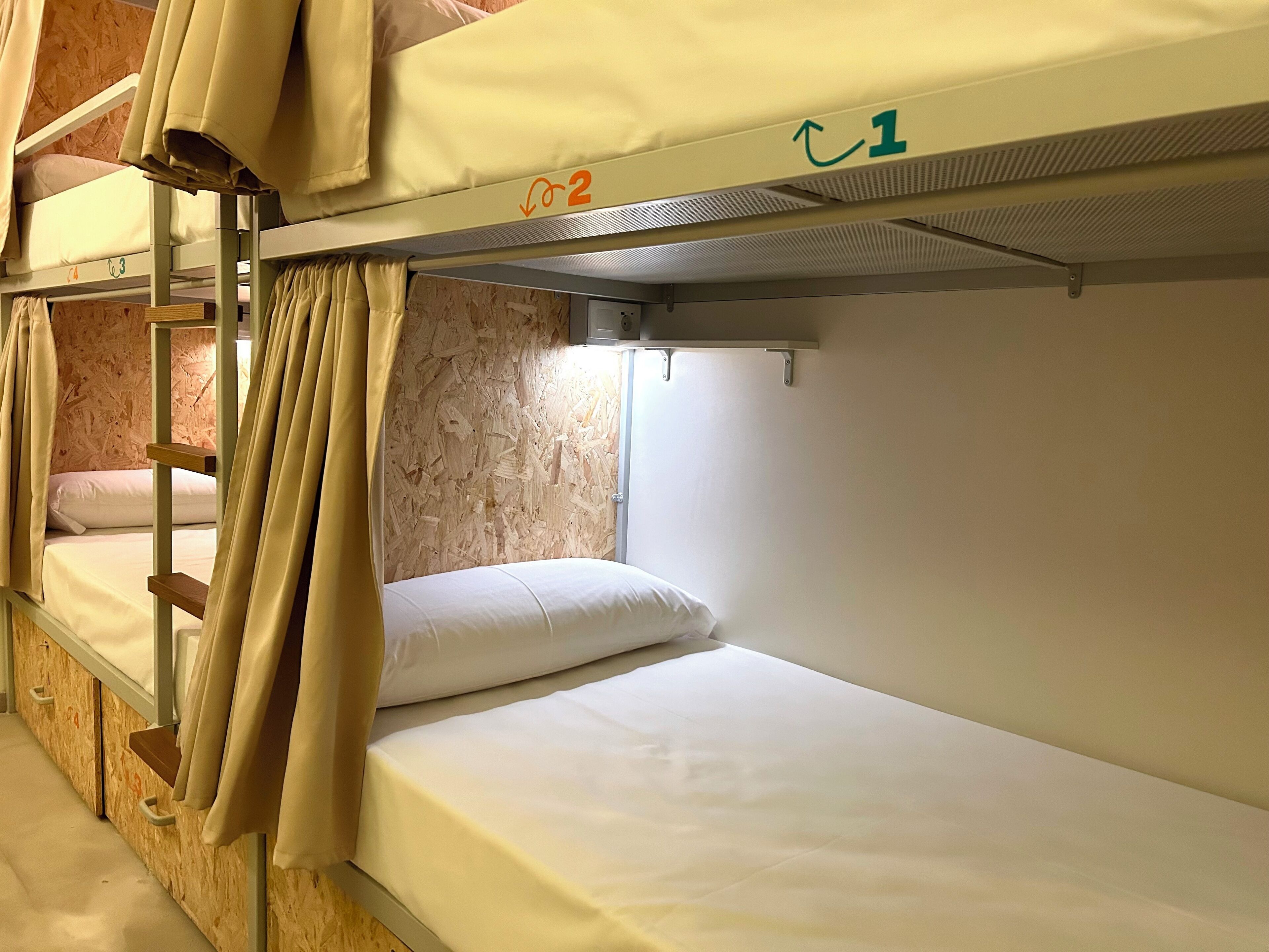 Quarto com beliche, parede de madeira, janela e cortinas.