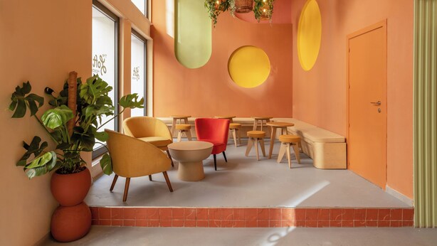 A modern interior with orange walls, a variety of seating options including chairs and tables, and decorative plants. - The Loft House Madrid (Madrid)