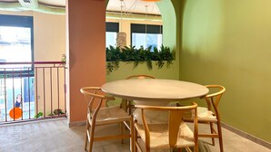 A dining area with a round table and four chairs, a red pendant light, and a green wall with a hanging plant. - The Loft House Madrid (Madrid)