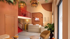 A modern hotel lobby with a red staircase, a reception desk, and a menu board. - The Loft House Madrid (Madrid)
