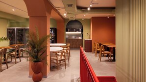 A restaurant interior with a kitchen, dining tables, chairs, and a red railing. - The Loft House Madrid (Madrid)