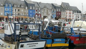 A harbor with several boats docked, including a blue and white boat named 'JOYEUXPECHEUR PAIMPOL'.