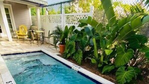 A rectangular pool with clear blue water, surrounded by lush green plants and a white fence. - Charming 1BR Cottage : Steps from Hemingway House & Old Town (Key West)