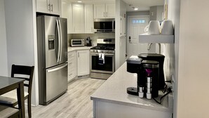 A modern kitchen with stainless steel appliances, white cabinetry, and a granite countertop. -   EXPLORE NEW SEABURY from our 2/2 Townhome - views + beach+ pool+ fireplace.  (Mashpee)