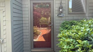A house with a gray siding exterior, a front door with a glass panel, and a mailbox. -   EXPLORE NEW SEABURY from our 2/2 Townhome - views + beach+ pool+ fireplace.  (Mashpee)