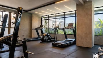 Un gimnasio con cintas de correr, una banca de pesas y una máquina de remo.