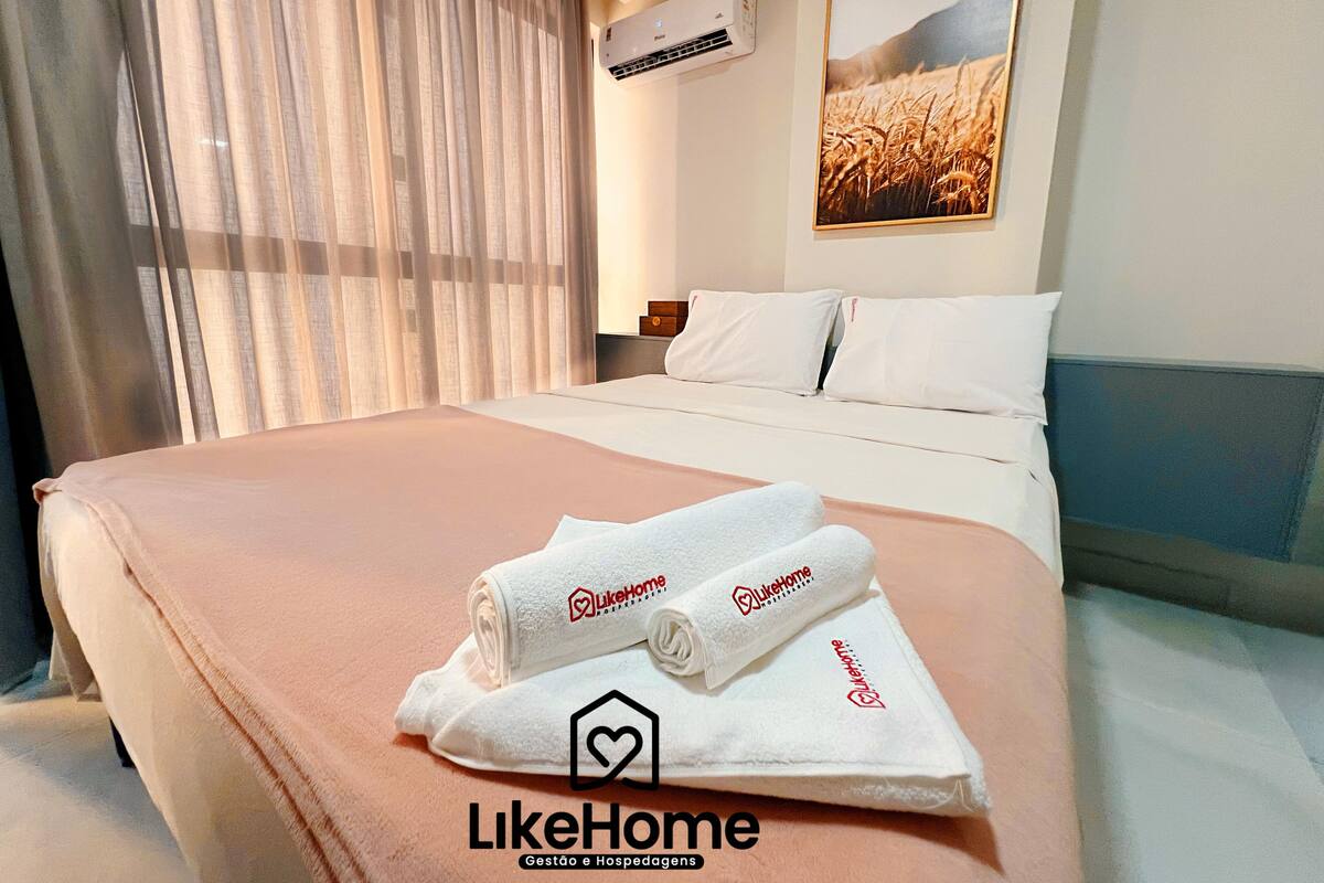 Habitación de hotel con una cama bien hecha, un cuadro en la pared y una ventana con cortinas.