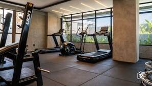 A gym with treadmills, a weight bench, and a rowing machine. - Co-House (João Pessoa)