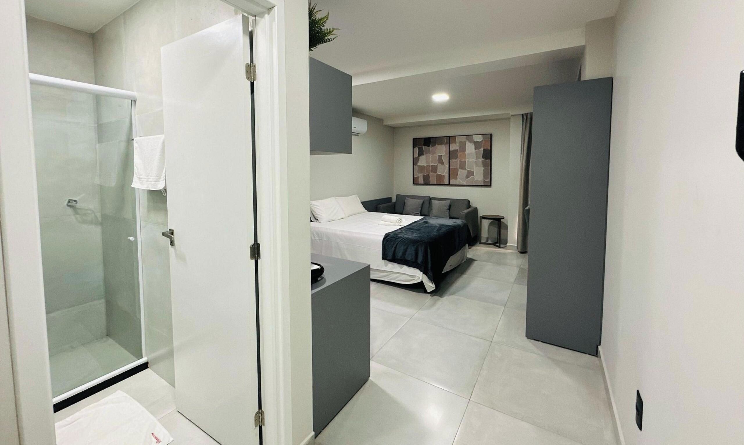 A hotel room with a shower, a bed, a sofa, and a small table.