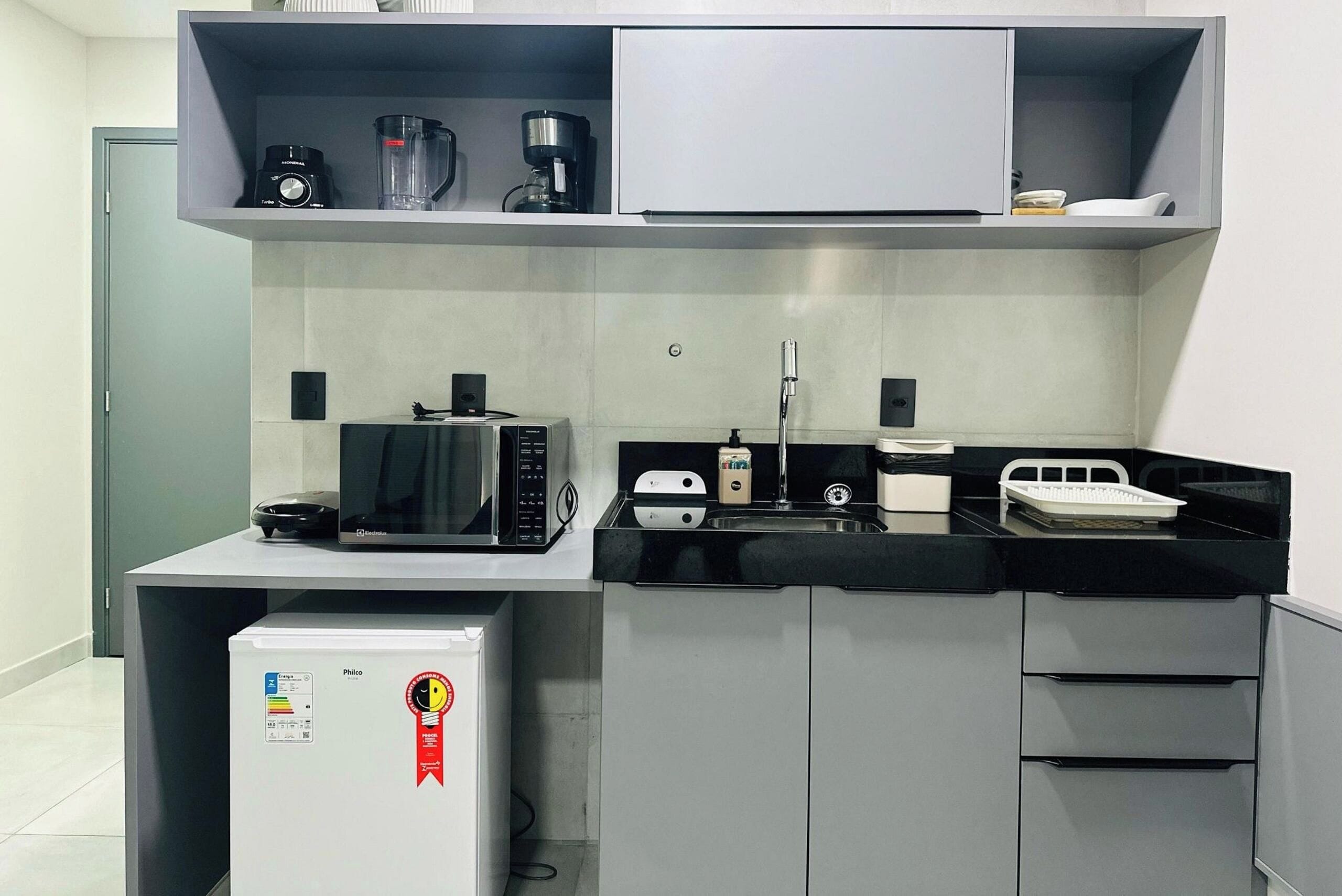 A compact kitchenette with a microwave, coffee maker, and a small refrigerator.