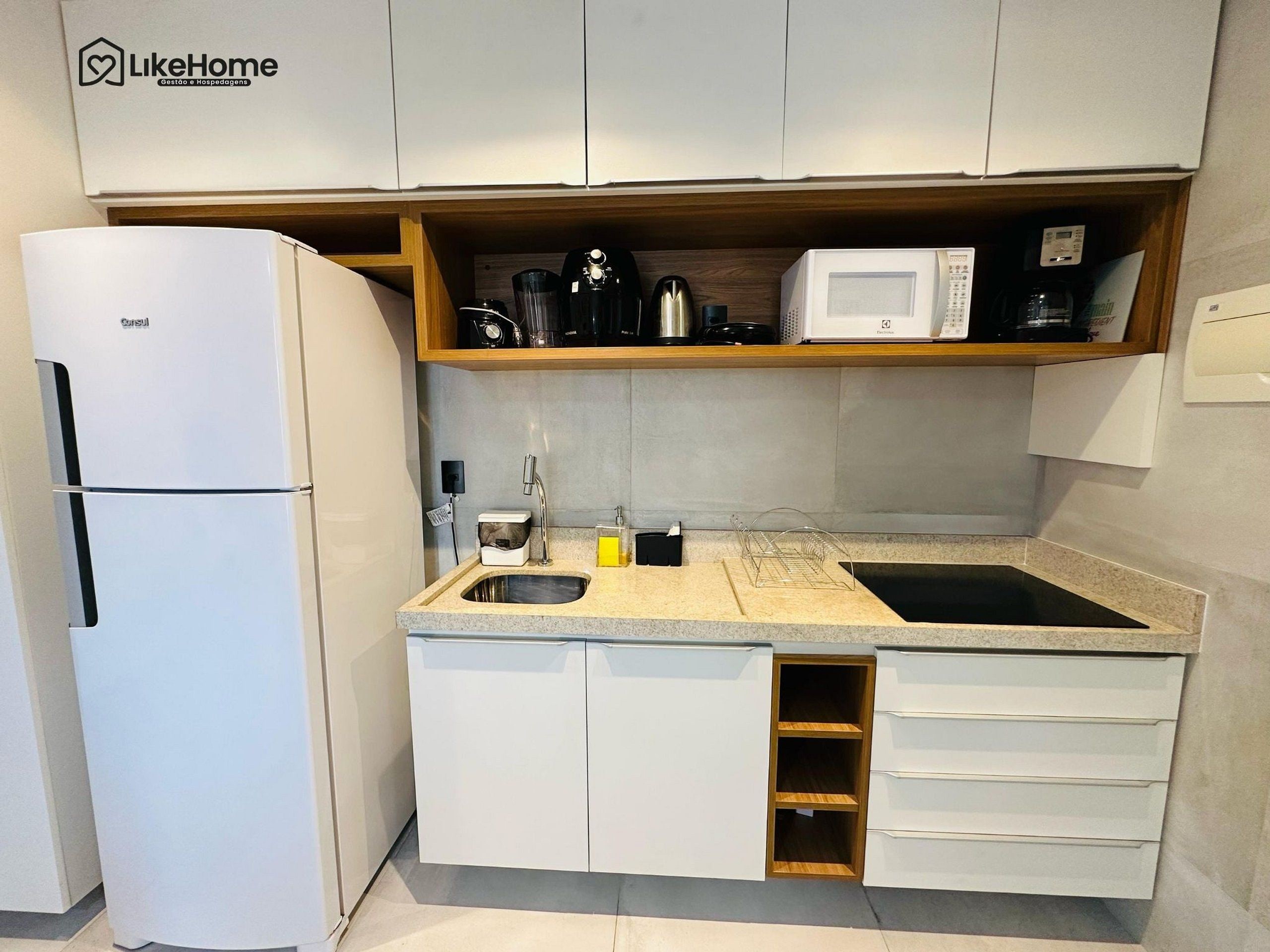 A compact kitchen with a refrigerator, a microwave, and a sink.