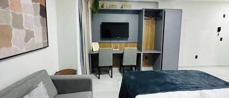 Une chambre d’hôtel moderne équipée d’un lit, d’un canapé, d’un bureau avec une chaise, d’une télévision et d’une armoire.