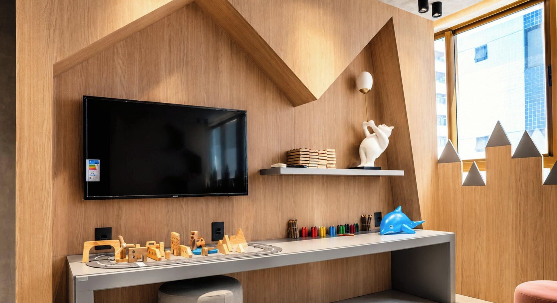 A modern living room with a flat-screen TV, wooden toys, and a white cat statue.