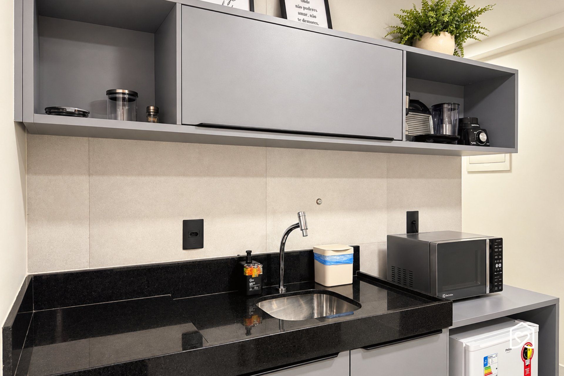 A modern kitchen with a black countertop, stainless steel sink, and a microwave.