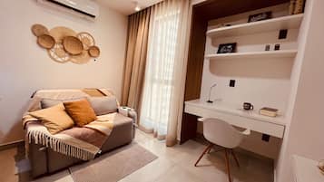 Quarto moderno com sofá, escrivaninha e uma cadeira.