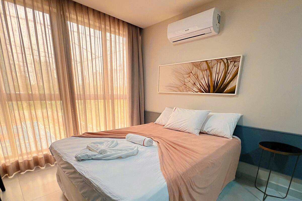 Una habitación de hotel con cama, escritorio, silla y ventana con cortinas.