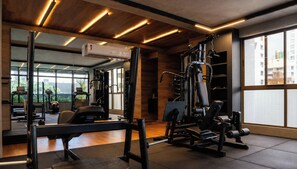 A gym with various exercise equipment, large windows, and a modern design. - Co-House (João Pessoa)