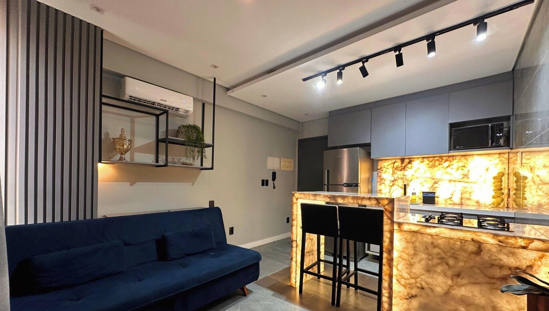 A modern kitchen with a marble countertop, a built-in microwave, and a stainless steel refrigerator.