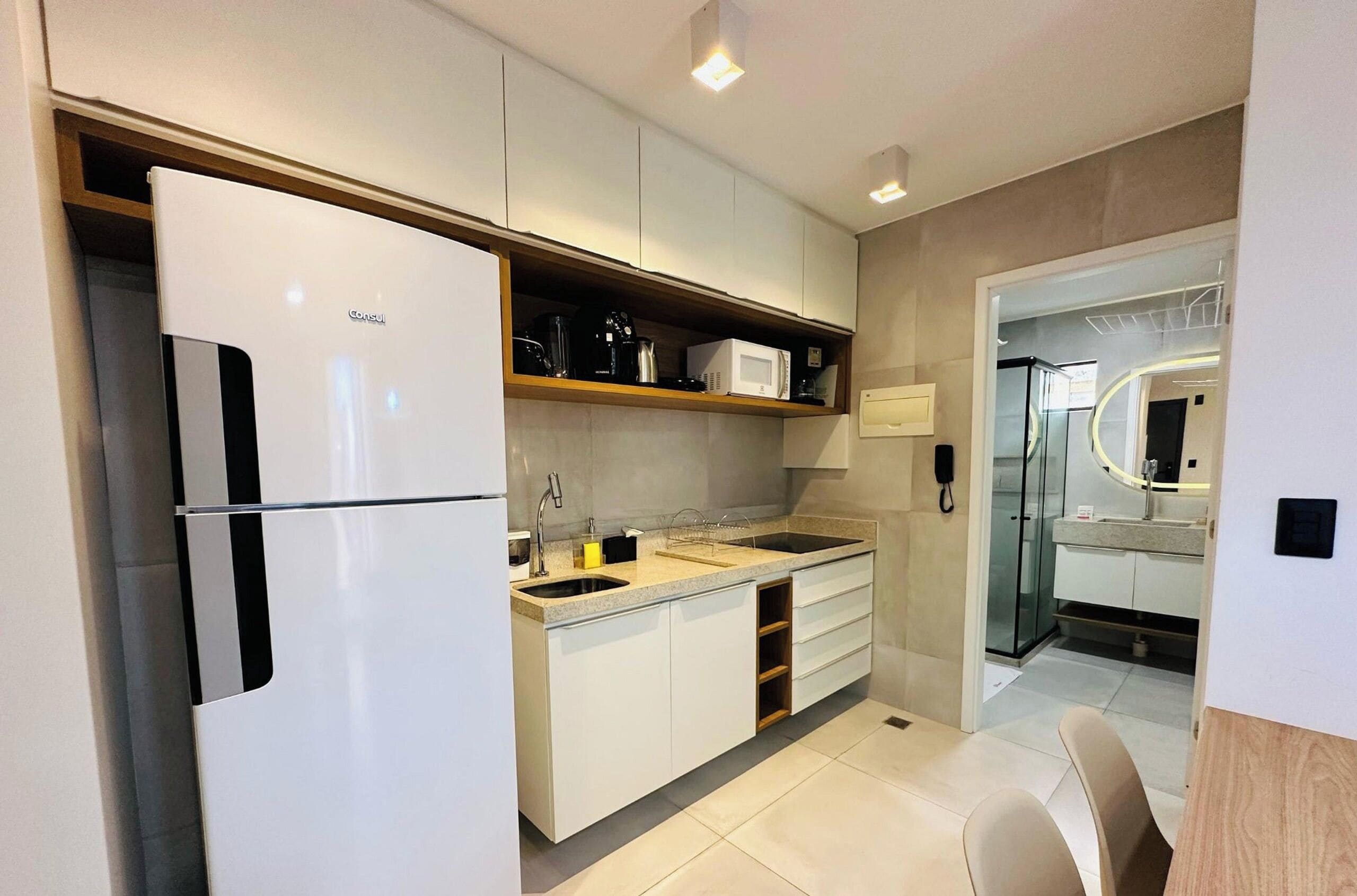 A modern kitchen with a built-in refrigerator, a double sink, and a microwave on the countertop.