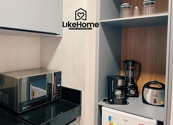 A kitchenette with a microwave, coffee maker, and a blender. - Co-House (João Pessoa)