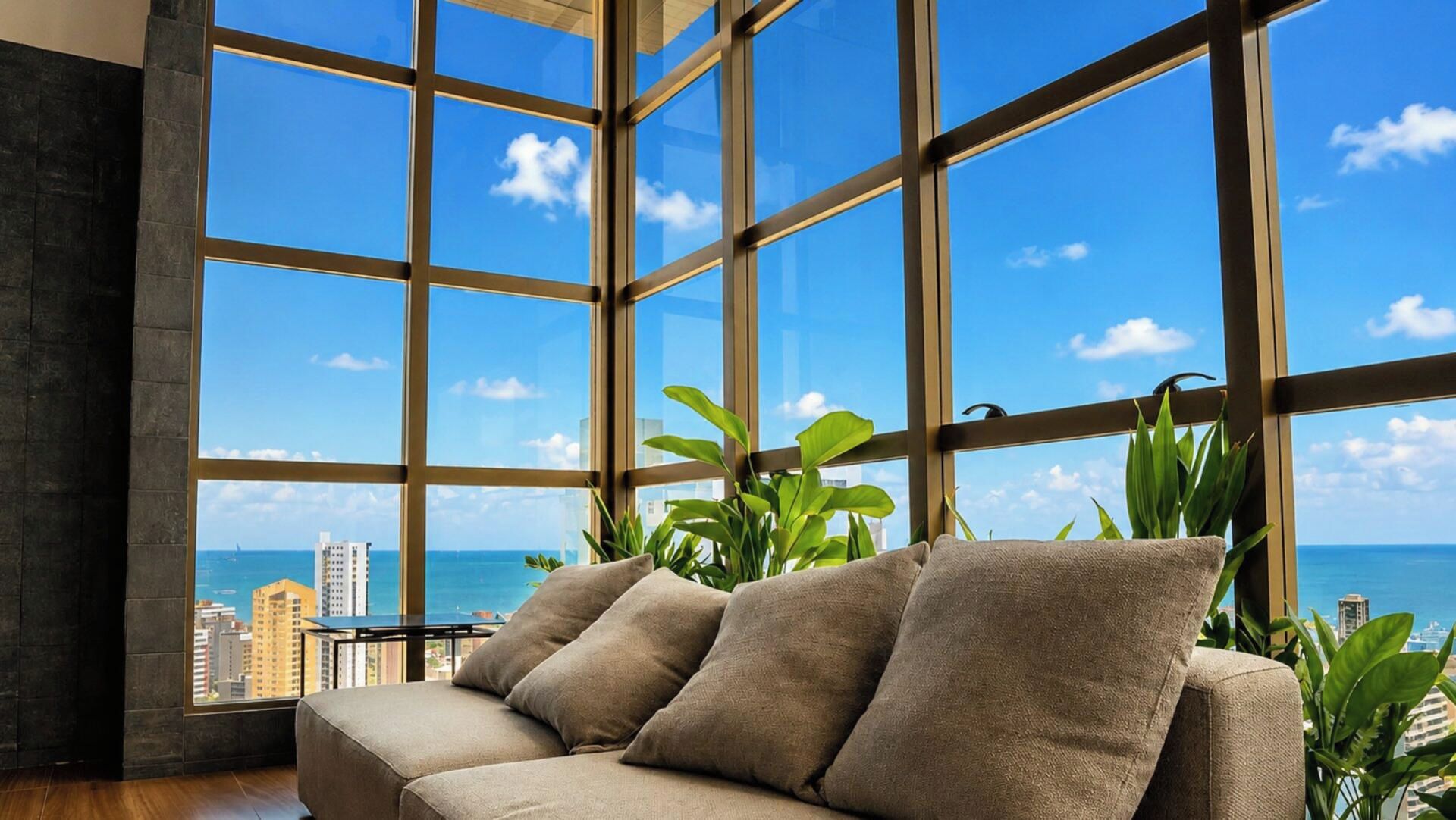 Ein modernes Interieur mit einem großen Fenster, das Meer und Stadtpanorama zeigt.