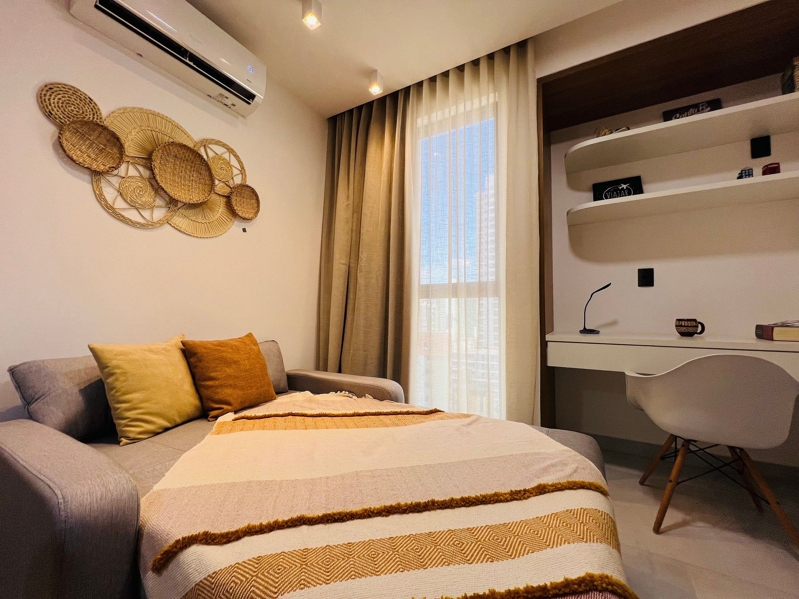 Un dormitorio moderno con sofá, escritorio y ventana grande.