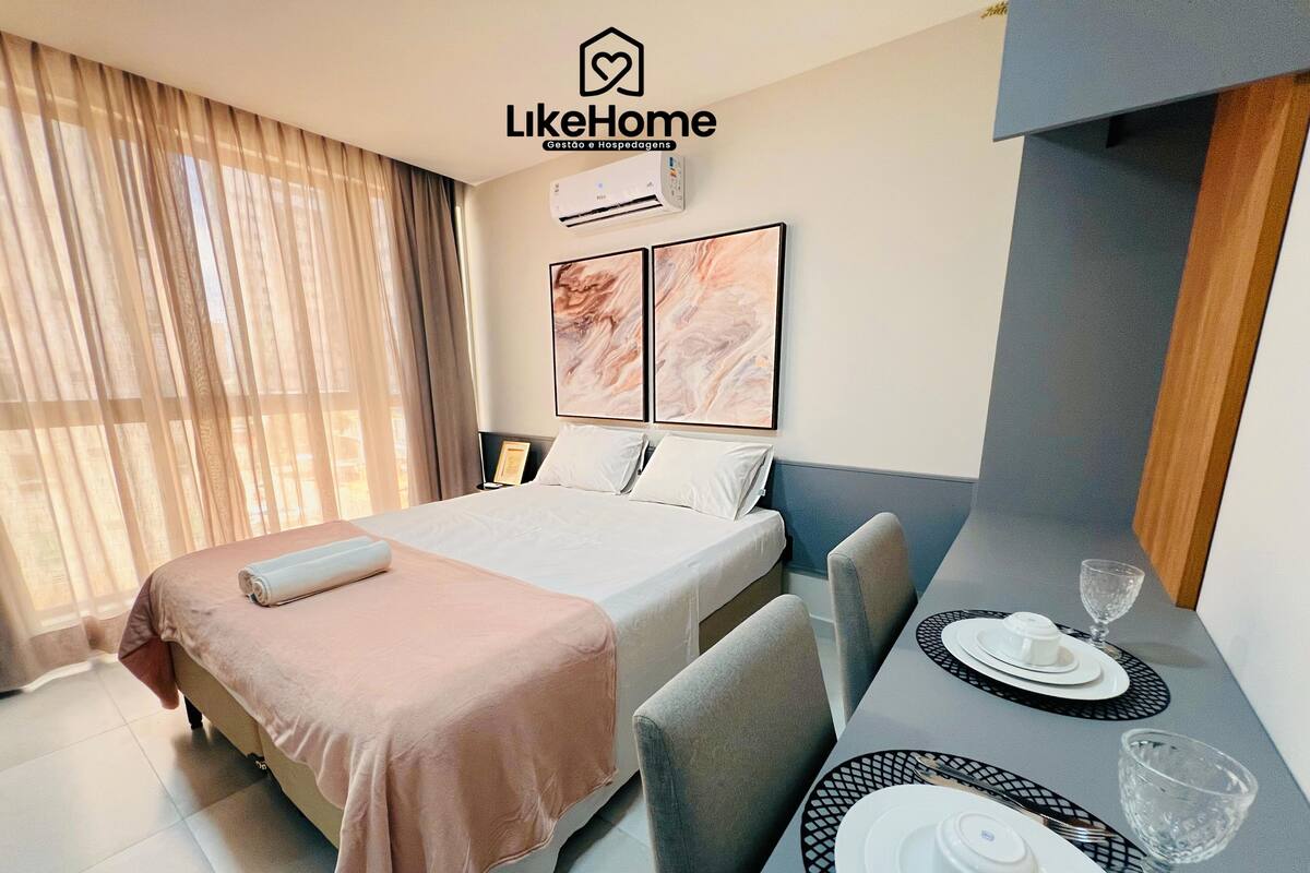 Habitación de hotel con cama, una mesa de comedor con platos y un vaso, y un aire acondicionado de pared.