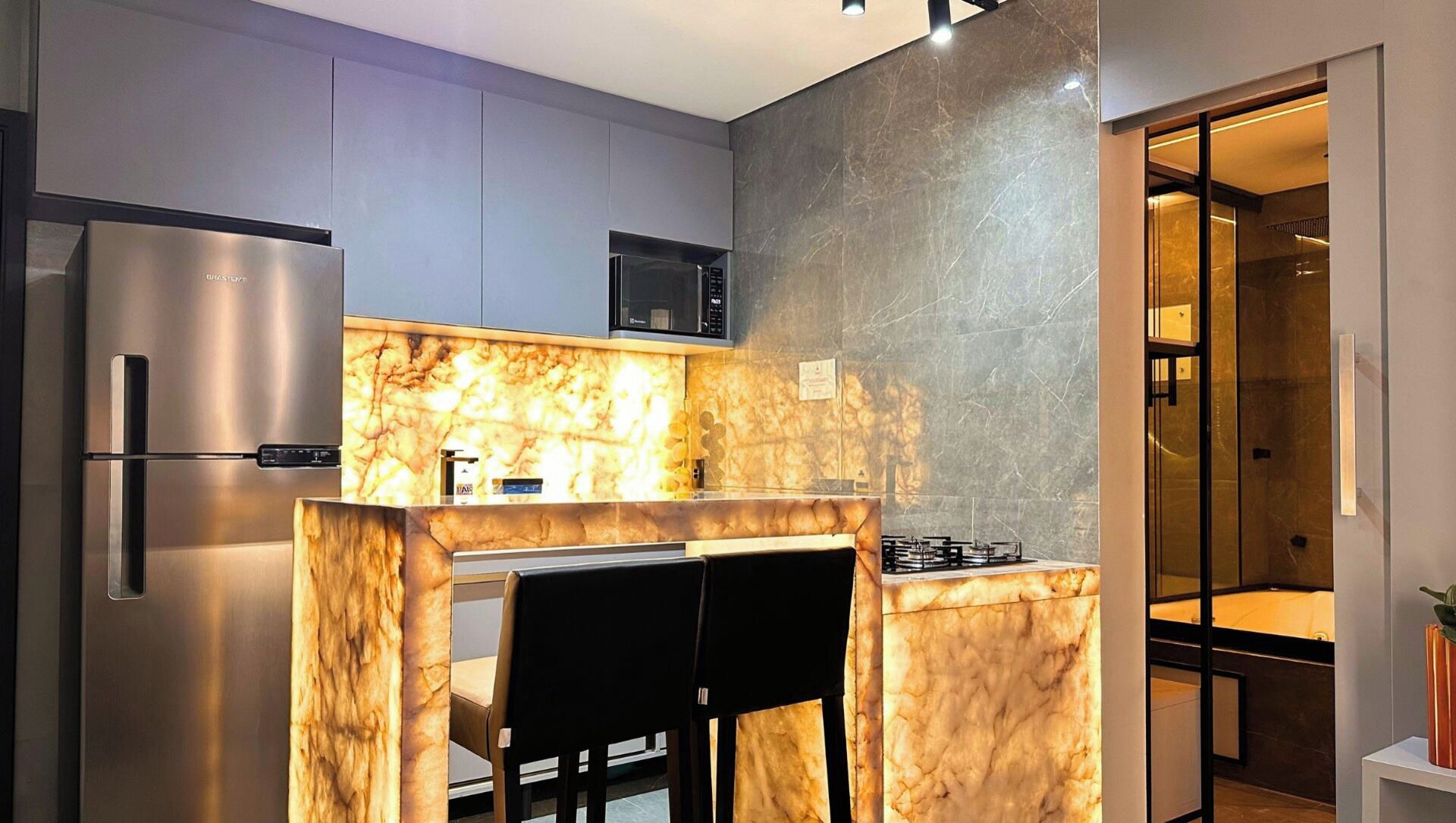A modern kitchen with a marble backsplash, stainless steel appliances, and a dining area with a black chair.