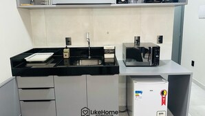 A compact kitchen with a sink, a coffee maker, a blender, and a microwave. - Co-House (João Pessoa)